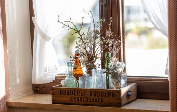 Fensterbank mit Flaschen und Blumen in der Gaststube