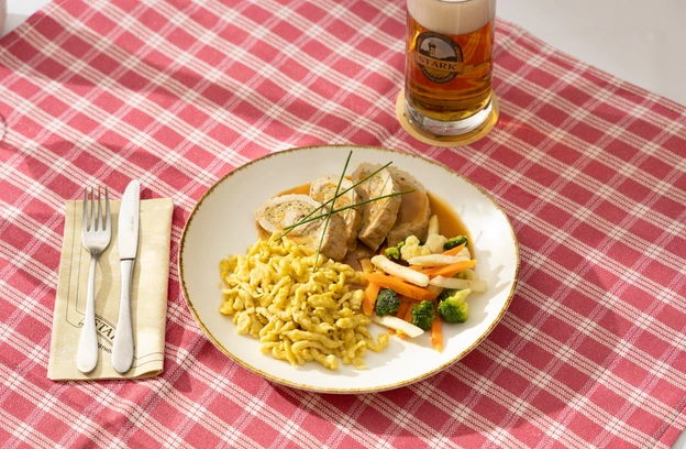 Schw&auml;bischer Teller mit Sp&auml;tzle und Gem&uuml;se auf kariertem Tischtuch