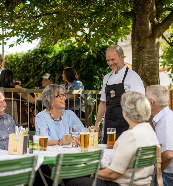 Gastgeber Josef Stark im Gespr&auml;ch mit G&auml;sten im Biergarten